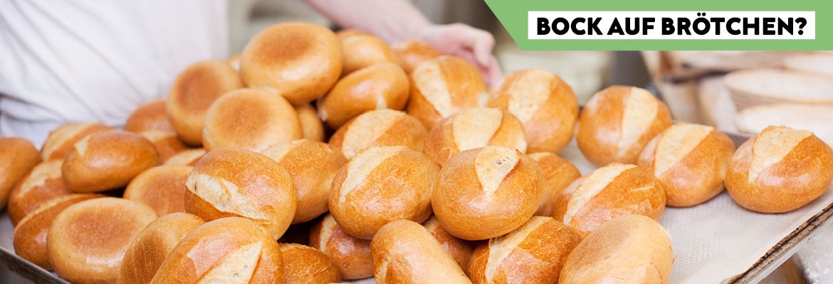 Bock auf Brötchen? Ein Bäcker zeigt frisch gebackene goldbraune Brötchen auf einem Backblech.